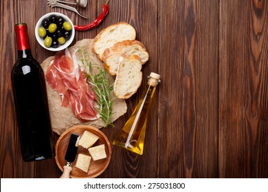 Prosciutto, wine, olives, parmesan and olive oil on wooden table. Top view with copy space  - Powered by Shutterstock