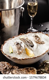 Prosecco bar concept. Open oysters lie on crushed ice with lemon and lime, next to a glass of champagne. Background image. Copy space.