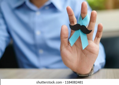 Prostate Cancer Awareness, Man hand holding light Blue Ribbon with mustache for supporting people living and illness. Men Healthcare and World cancer day concept