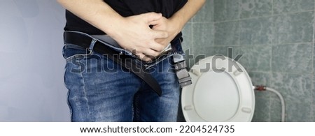 Prostatitis concept. Rear view of a man, hard to pee. Difficulty urinating with prostatitis. View of the toilet and the legs of a man. Imitation of urine with clear water. Sick in the toilet