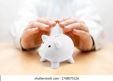 Protect your money. Small piggy bank covered by hands - Powered by Shutterstock