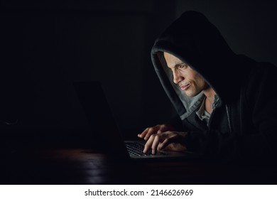 Protect Yourself Before Its Too Late. Shot Of A Hooded Computer Hacker Using A Laptop In The Dark.