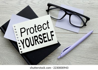 PROTECT YOURSELF on a black notebook, torn paper with a sticke - Shutterstock ID 2230000943