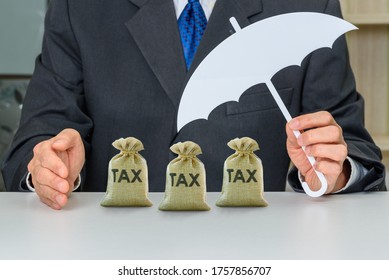Protecting individual income from tax, financial concept : Taxpayer uses a hand and umbrella to protect tax bags, depicts avoiding from tax burden by using serveral methods e.g tax deduction, etc
