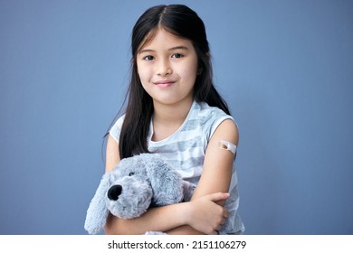 Protecting our children. Shot of an adorable little girl sitting in the studio after getting her Covid vaccine and holding a teddy bear.
