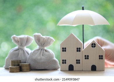 Protection, Coins money in the bag under the umbrella and model house on natural green background, Finance insurance and Safe investment concept
