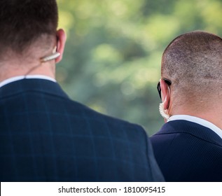 Protection And Guard Service. Bodyguard Man With Earphone And Black Eyeglasses And Business Suit Wearing A Mask During The Covid-19 Outbreak, During A Public Visit Of A Dignitary.