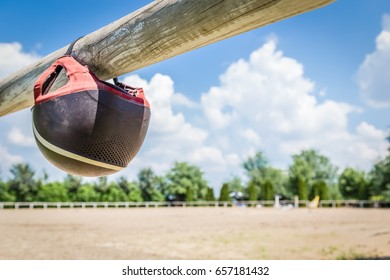 Protection Horse Riding Helmet Hanging On Fence Of Outdoor Equestrian Arena.