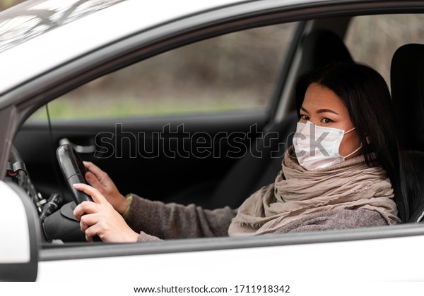 Protection from the virus. Woman driving car in\
medical mask