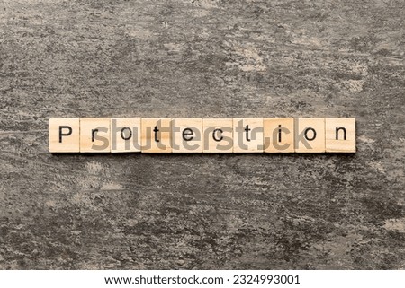 PROTECTION word written on wood block. PROTECTION text on cement table for your desing, concept.