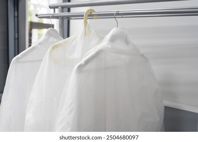 Protective gowns hang neatly at the entrance to a food production facility. hygiene and safety measures in the workplace: uniforms are ready for workers before entering. High quality photo - Powered by Shutterstock