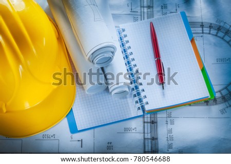 Protective hard hat checked notebook pen blueprints on construction plan.