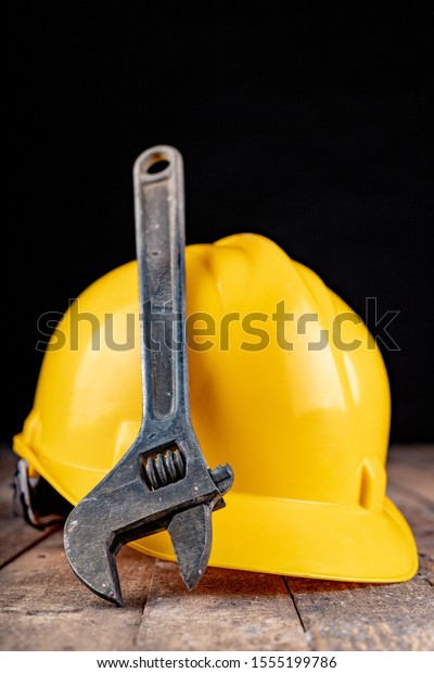 Protective helmet and wrench. Work
accessories for production workers. Dark
background.