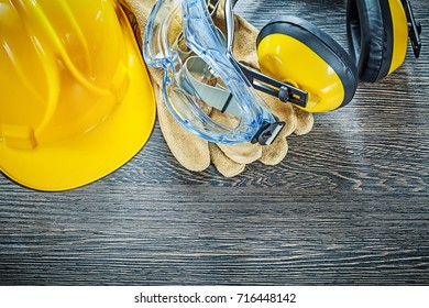 Protective leather gloves goggles earmuffs hard hat on wood boar - Shutterstock ID 716448142