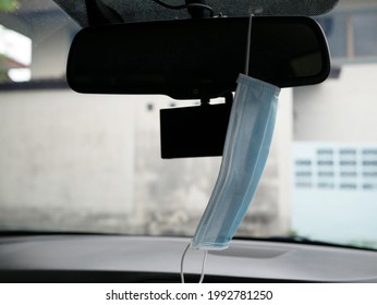 Protective Mask Hanging On Rear View Mirror In A Car.