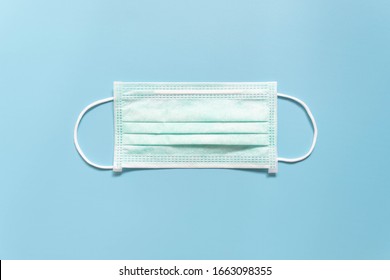 Protective Medical Face Mask On Light Blue Background. Devices Designed To Protect The Wearer From Inhaling Airborne Bacteria, Virus Or Dust Particles. Health Care. Top View.