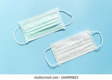 Protective Medical Face Mask On Light Blue Background. Devices Designed To Protect The Wearer From Inhaling Airborne Bacteria, Virus Or Dust Particles. Health Care. Front And Back Side.