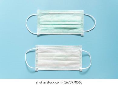 Protective Medical Face Mask On Light Blue Background. Devices Designed To Protect The Wearer From Inhaling Airborne Bacteria, Virus Or Dust Particles. Health Care. Front And Back Side.