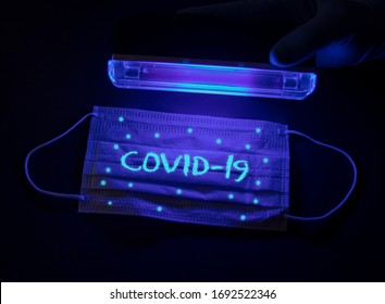 Protective medical mask with the inscription Covid-19 and with small coronavirus molecules under an ultraviolet lamp