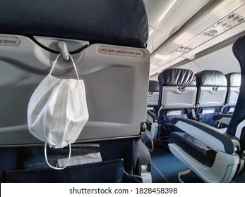 Protective Medical White Safety Mask Hanging In Airplane For Covid-19, Travel And Coronavirus Concept Close-up