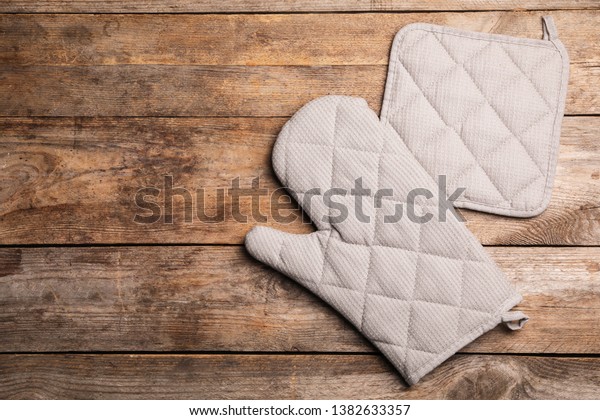 Protective oven glove and potholder on wooden table,\
top view with space for\
text