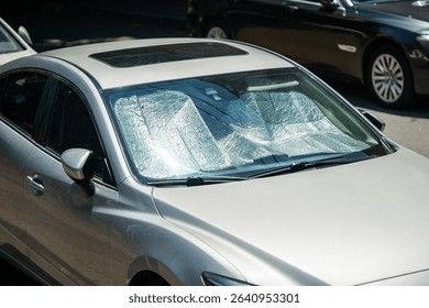Protective reflective surface under the windshield of passenger car parked on hot day, heated by sun rays inside car. Sunshade, Heat protection, auto accessory concept