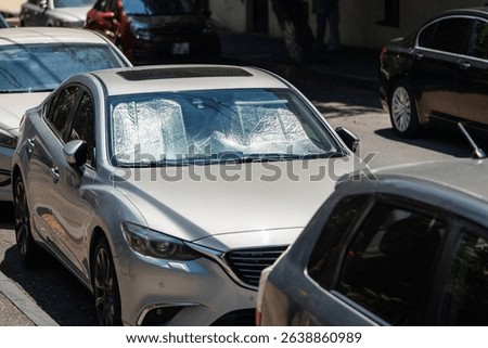Protective reflective surface under the windshield of passenger car parked on the city street on hot day, heated by sun rays inside car. Sunshade, Heat protection, auto accessory concept