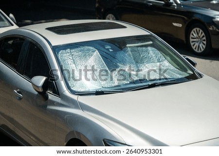 Protective reflective surface under the windshield of passenger car parked on hot day, heated by sun rays inside car. Sunshade, Heat protection, auto accessory concept
