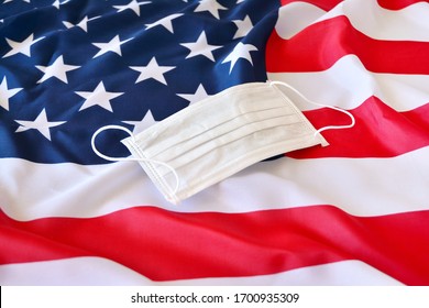 Protective Surgical Face Mask On American National Flag. Coronavirus In USA  Fllag With Protective Mask Over To Protect Epidemic In America.