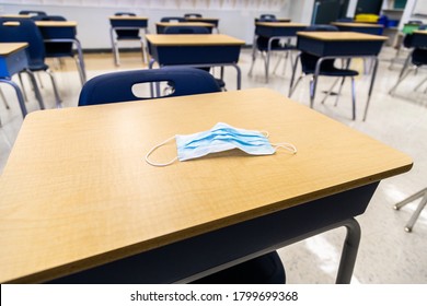 Protective Surgical Mask Resting On A Student Desk Within A Clean Contemporary Classroom