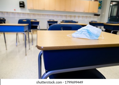 Protective Surgical Mask Resting On A Student Desk Within A Clean Contemporary Classroom