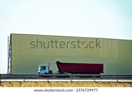 Protective wall on the highway protects from dust and noise (noise screen, sound-proof wall), high noise level. Different types of light and heavy transport on the background of the wall