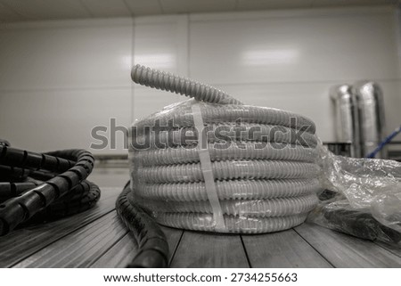 Protective white cable conduit coiled and taped on a warehouse shelf.