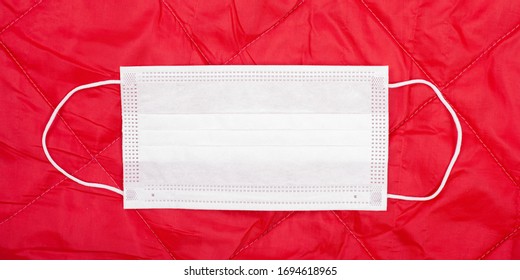 Protective White Medical Mask On A Red Background. Pandemic Response Measure Viral Coronavirus, Stay At Home Quarantine.