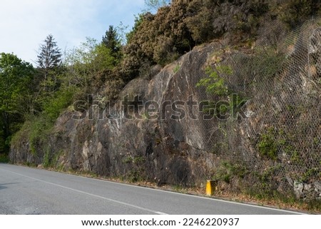 Protective wire mesh against falling rocks. Protection or caution on mountain road. Safety net for rockfall on cliff.