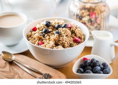 Protein Granola Made From Oat Porridge, Nuts, Seeds, Berries In The Bowl With Table Set For Breakfast