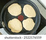 Protein Pancakes Cooking on Non-Stick Pan. Healthy Breakfast in Progress on Speckled Skillet. Four Fluffy Batter Rounds on Dark Granite Cookware