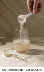 Protein powder added with measuring scoop in a glass of water. Nutrition and food supplement