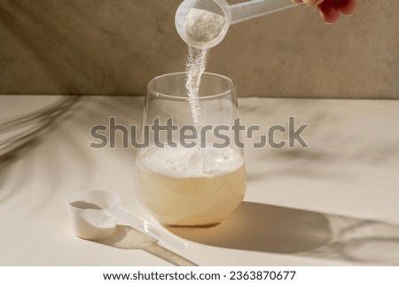 Protein powder added with measuring scoop in a glass of water. Nutrition and food supplement