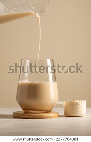 Protein powder. Pouring chocolate drink in a glass.