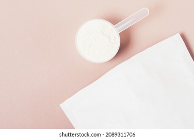 Protein Powder In Scoop Next To Paper Bag On Light Brown Background With Copy Space, Flat Lay