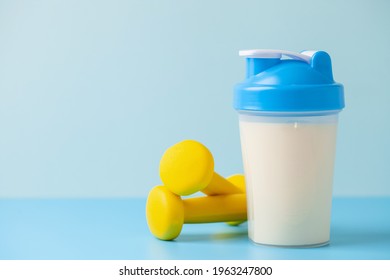 Protein Sport Shake And Dumbbells  On Blue Background . Fitness Food And Drink. Diet. Copy Space