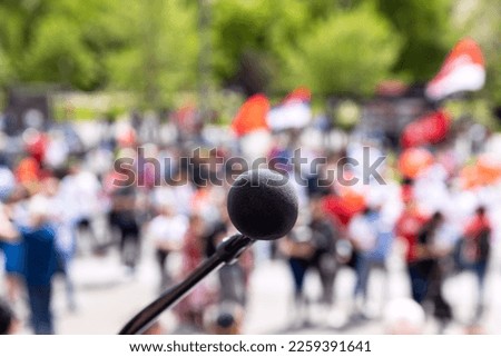 Protest, public demonstration or pension reform strike, focus on microphone, blurred crowd of people in the background