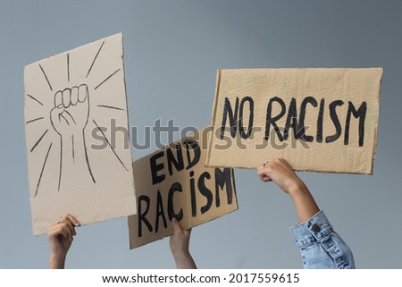 protest white and black hands holding cardboard poster with message text END RACISM on white background. Concept on the theme of prostate in minneapolis and police aggression of racism.