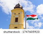 The Protestant Great Church (Református Nagytemplom) in Debrecen, Hungary with the hungarian national flag on blue sky background.