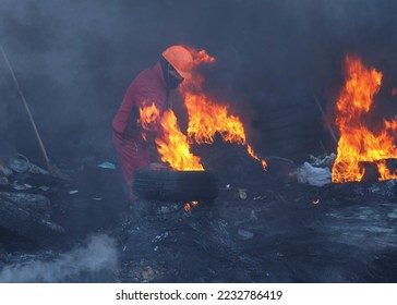 Protester in helmet burn tires on the Maidan barricades to stop the riot police during Mass anti-government protests Euromaidan on January 2014 in Kyiv, Ukraine  - Shutterstock ID 2232786419