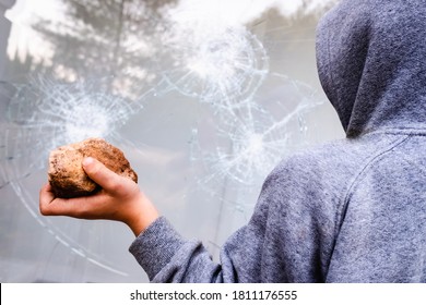 Protester Holding A Rock To Break The Glass Of A Shop Window In The Street During Protests.