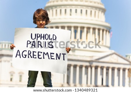 Protester holding sign uphold Paris agreement in hands