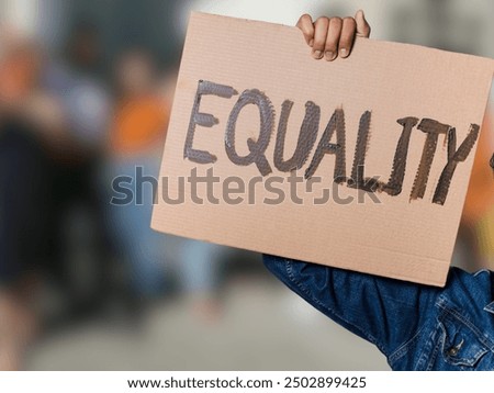 A protester holds up a cardboard sign reading 