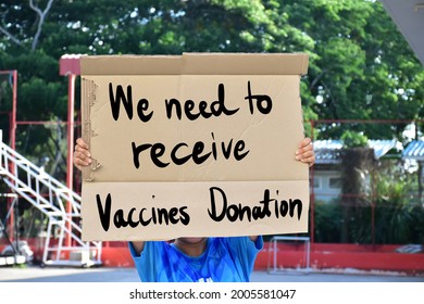 Protester Holds White Paper Which Has Texts 'We Need To Receive Vaccines Donation.' Concept For Calling The Covid-19 Vaccines Donation From The Rich Countries To The Poor Countries Around The World.